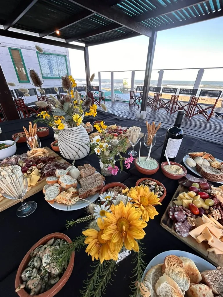 Mesa de catering y picada gourmet servida en el deck de madera con vista al mar abierto