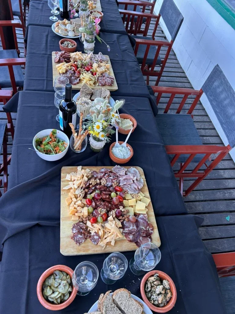 Gran tabla de fiambres artesanales, quesos seleccionados y copas de vino sobre el deck