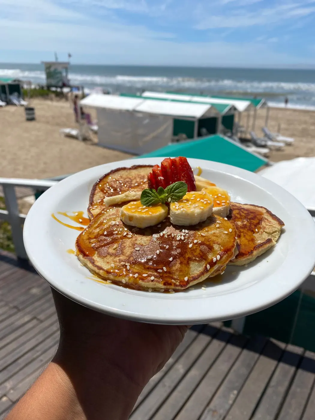 Pancakes con banana y frutillas frente al mar